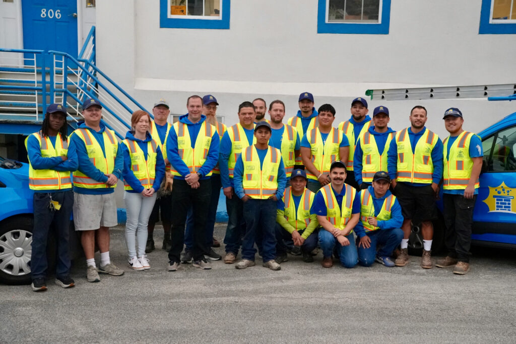 the Chimney Scientists team dressed in safety vests poses in front of the company's warehouse, ready to provide chimney services in Media, PA
